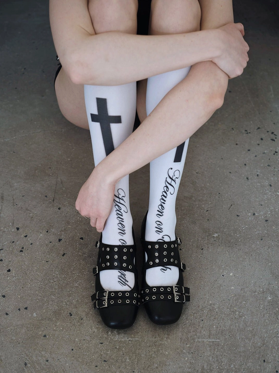Black studded platform Mary Jane flats styled with white gothic cross print knee-high socks in an overhead view