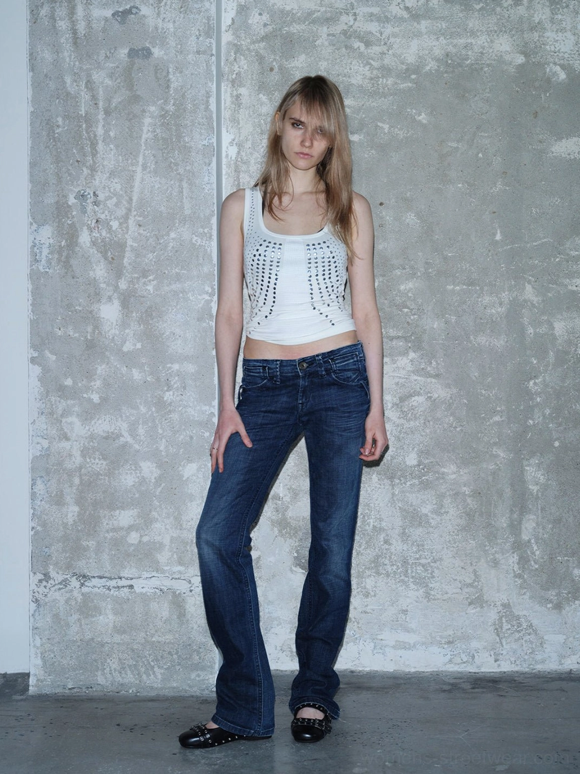 Black studded platform Mary Jane flats styled with a white studded tank top and low-rise flared jeans