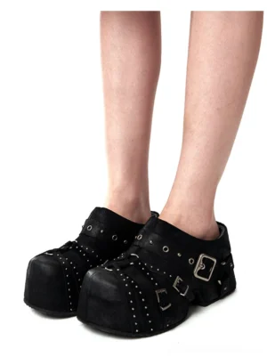 Close-up of black studded platform slip-on mules worn with multiple silver buckles and chunky streetwear soles