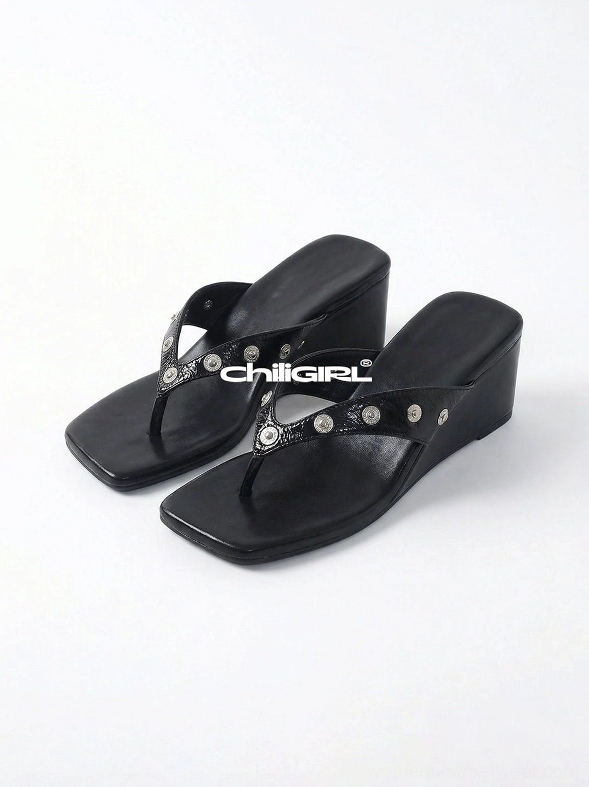 Pair of black studded platform thong sandals with silver round studs, square open toes, buckle accents, and thick wedge soles