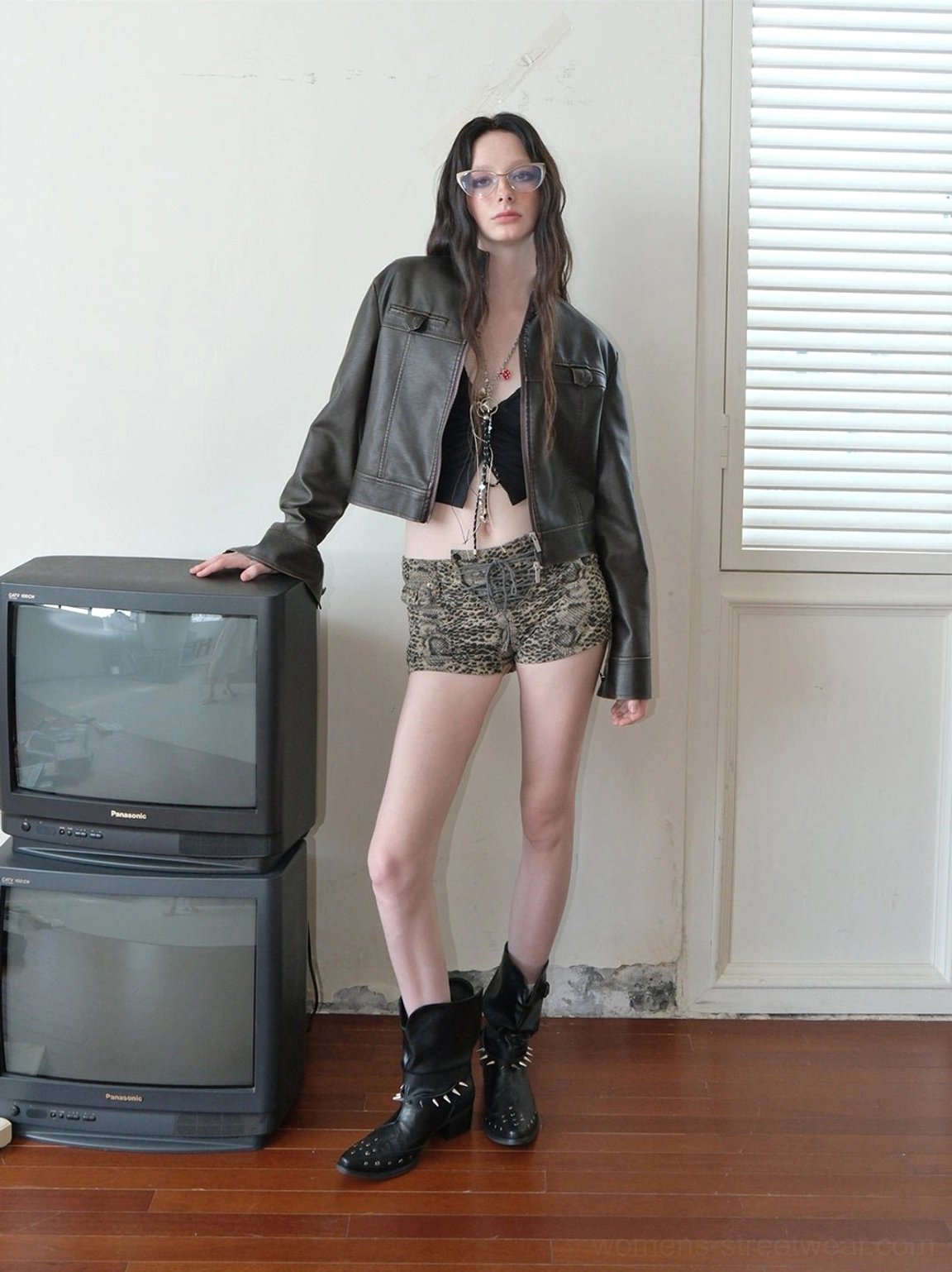 Black studded pointed-toe ankle boots styled with leather jacket cropped top and leopard print shorts