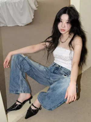 Female model wearing black studded pointed-toe slingback kitten heels with wide-leg jeans in a casual streetwear outfit