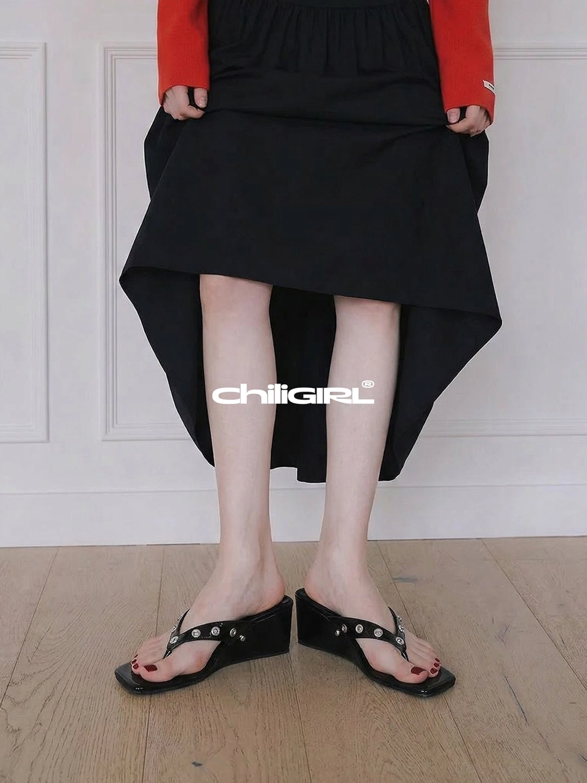 Full lower-body outfit featuring black studded wedge thong sandals styled with a high-low black skirt and red-sleeved top