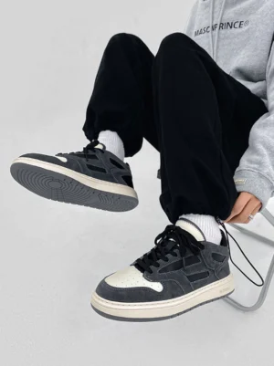 Model wearing black suede-look low-top sneakers with white crew socks black joggers and gray hoodie streetwear outfit
