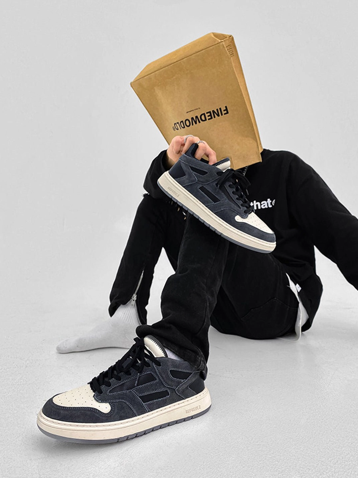 Black suede-look low-top streetwear sneakers with off-white sole shown in a creative black outfit and white socks