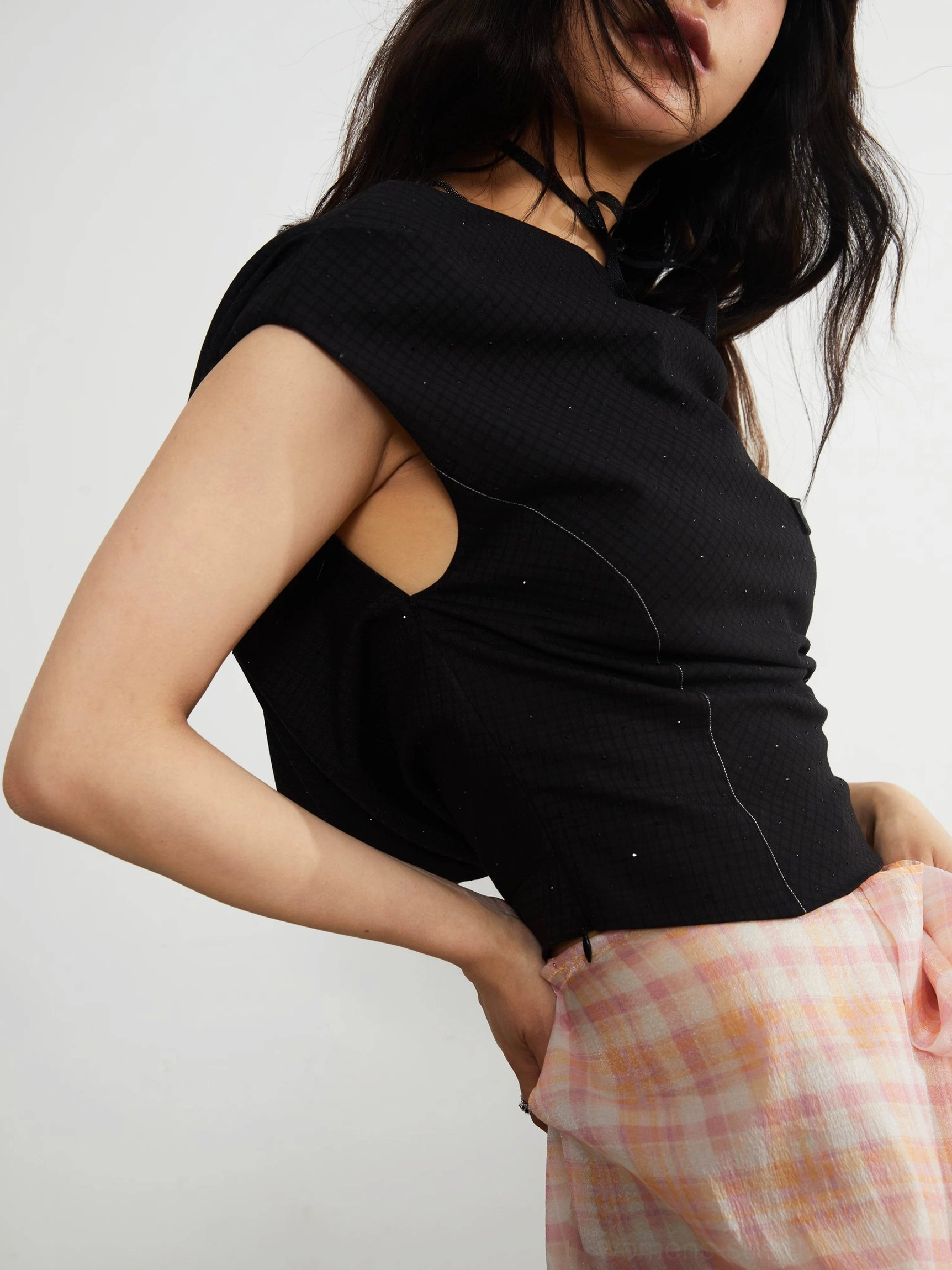 Close-up of black textured knit crop top shoulder cutout asymmetric neckline and contrasting topstitch details