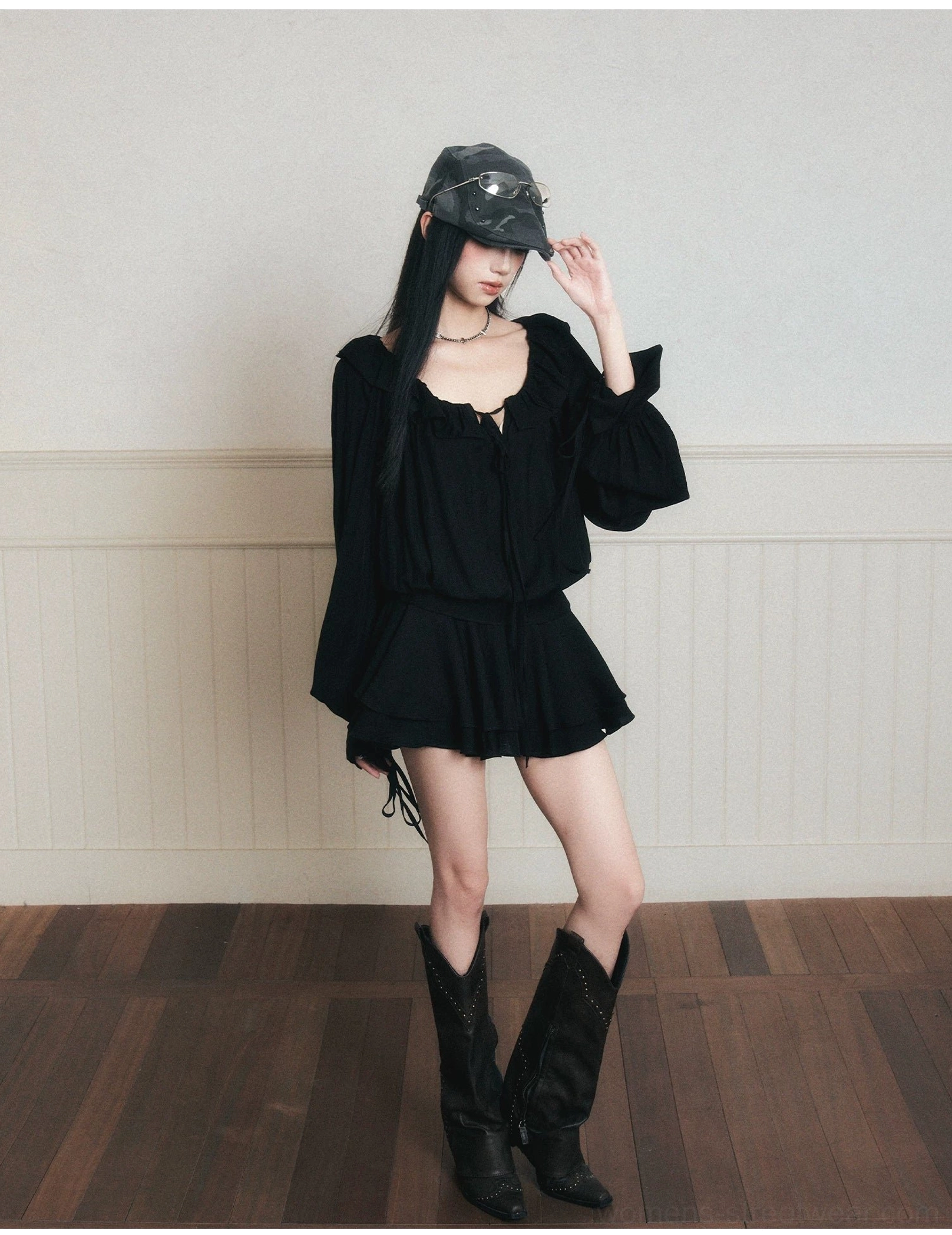 Three-quarter front view of black tie-front poet mini dress with ruched neckline, flared sleeves and ruffle skirt