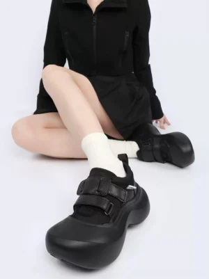 Women wearing black triple-strap sculpted platform shoes with white crew socks in an overhead streetwear outfit view