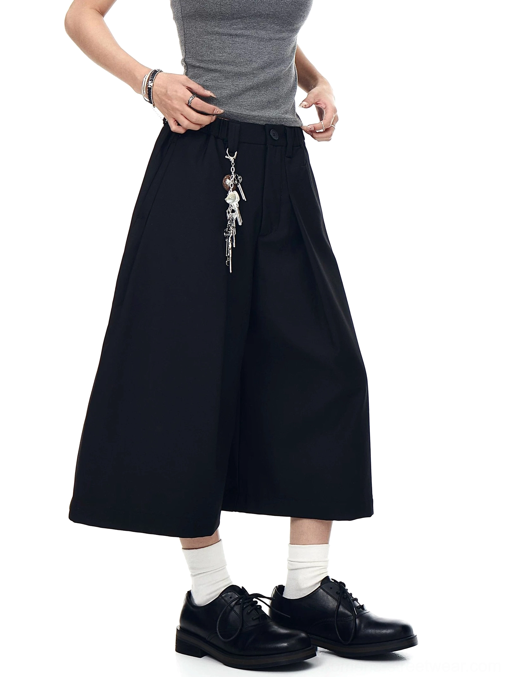 Black utility keyring culotte trousers shown from a side three-quarter view with front pleats and relaxed wide cropped legs