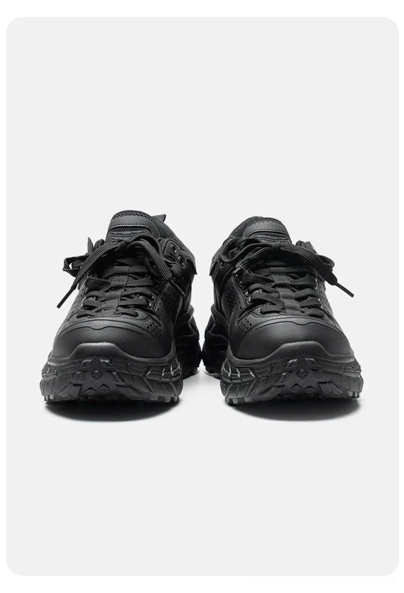 Front view of two black utility streetwear trainers with rounded toe caps complete lace systems and thick chunky lugged outsoles