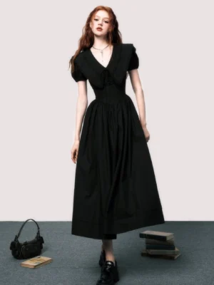 Full front view of a black V-neck puff sleeve A-line midi dress with bow neckline, cinched waist, and flowing skirt