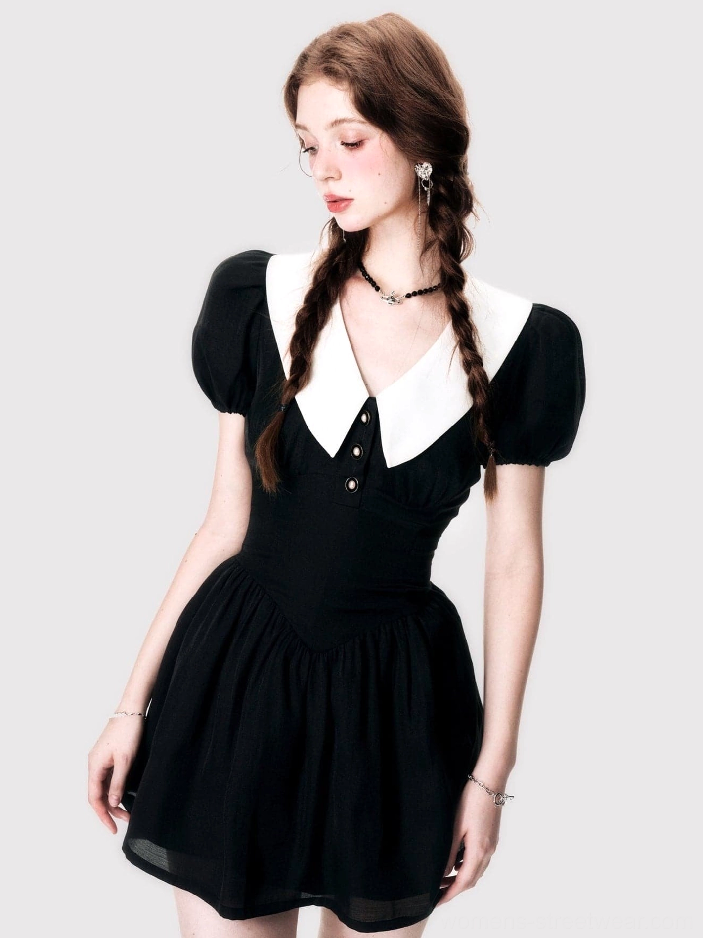 Right side view of a black contrast collar mini dress featuring a V-neck, half-button placket, cinched waist, puff sleeves, and gathered flared skirt