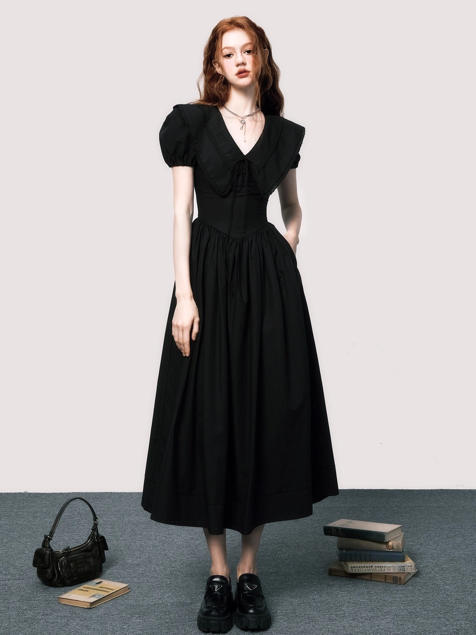 Angled front view of black V-neck puff sleeve midi dress with high-waisted gathered skirt and tailored silhouette