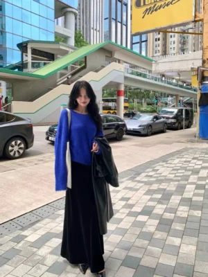 Black velvet A-line maxi skirt styled with a royal blue knit sweater in an urban streetwear outfit with a white shoulder bag