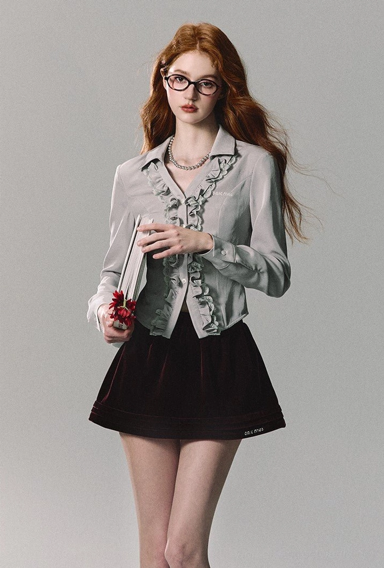 Black velvet A-line mini skirt with a cropped ruffled blouse and pearl necklace in a romantic streetwear look