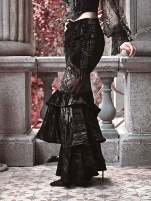 Black velvet lace ruffle mermaid skirt shown from a low side angle on a vintage stone balcony, featuring a fitted silhouette, sheer lace waist insert, and layered fishtail hem