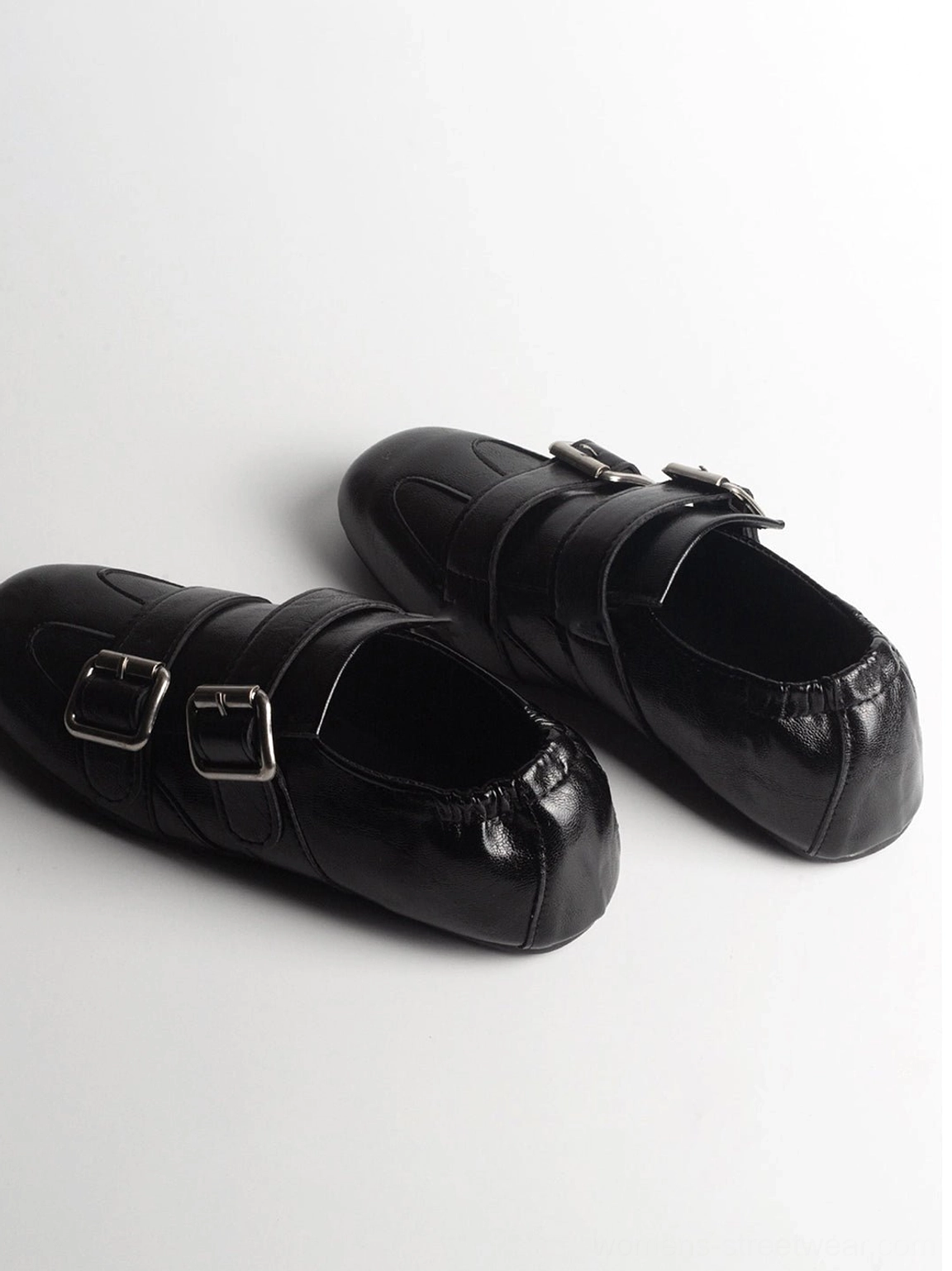 Black vintage-inspired double-buckle leather loafers shown in side flat lay view