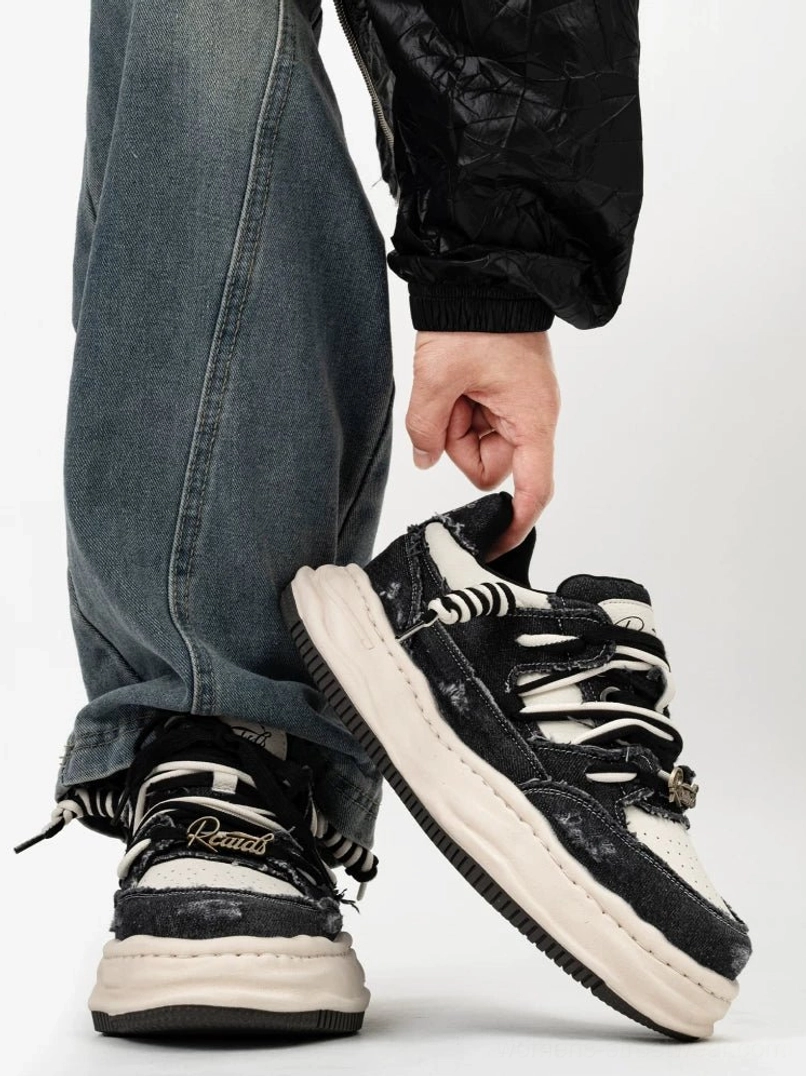 Black washed distressed skate sneakers with contrasting white toe cap and thick white midsole shown from a rear three quarter angle