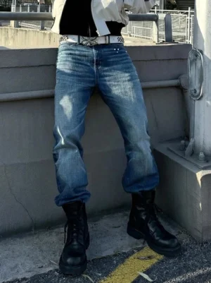Model wearing black washed horsehide combat boots with rear zipper detail and blue jeans in an urban streetwear setting