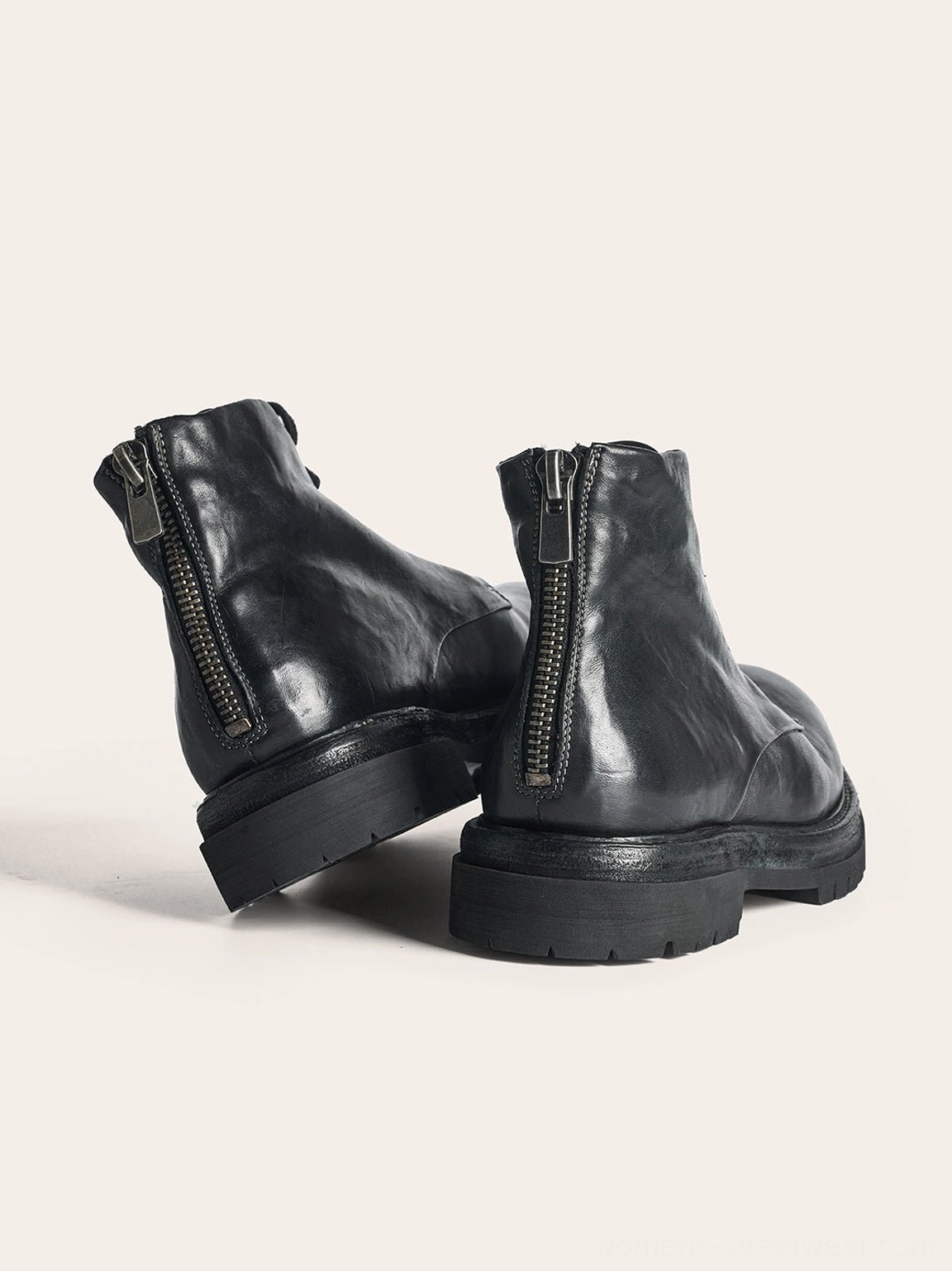 Rear view of black washed horsehide combat boots highlighting dual metal rear zippers, smooth leather heels, and thick blocky soles