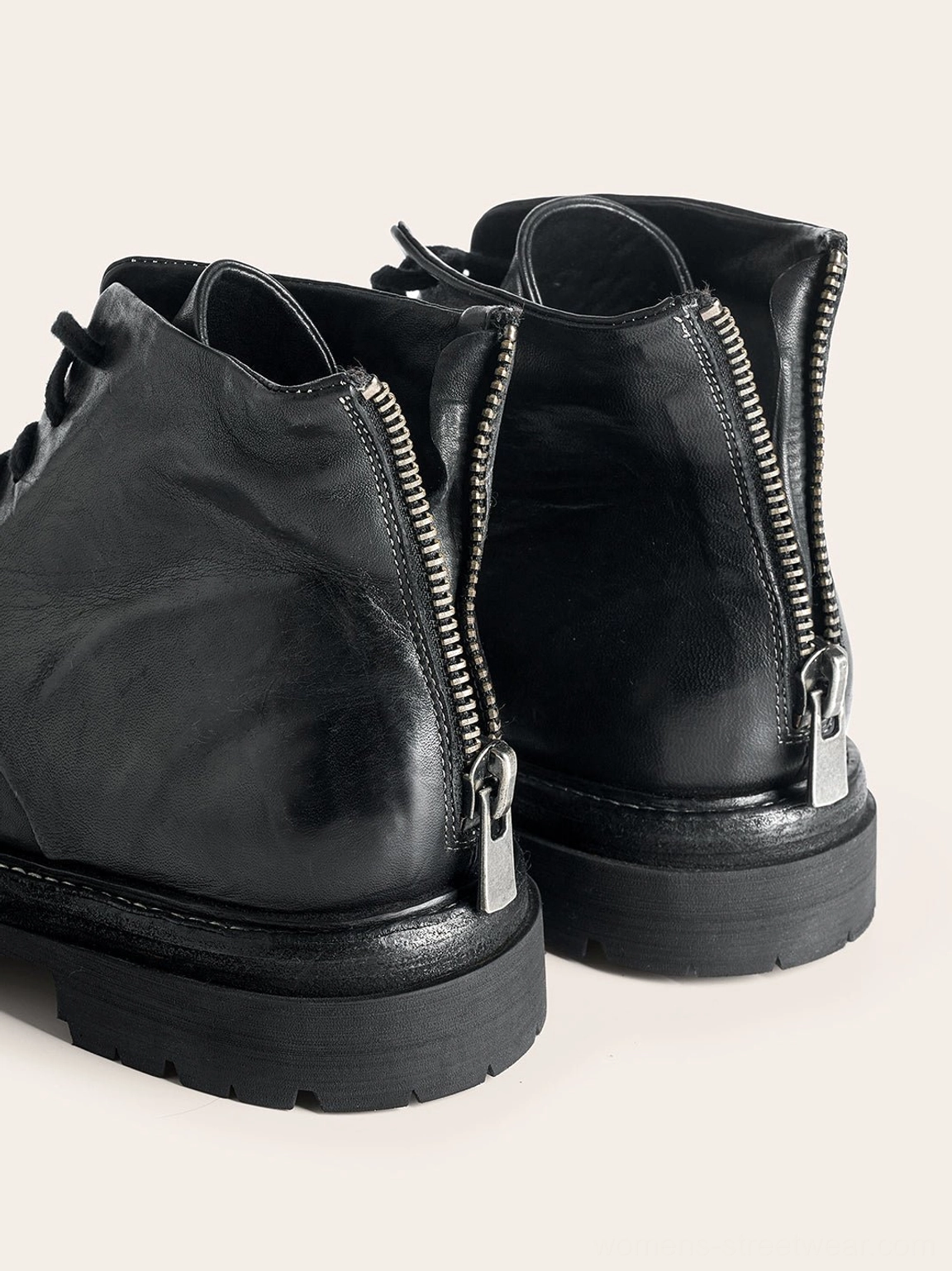 Black washed horsehide combat boots with rear zipper closure and chunky lug outsole for unisex streetwear styling