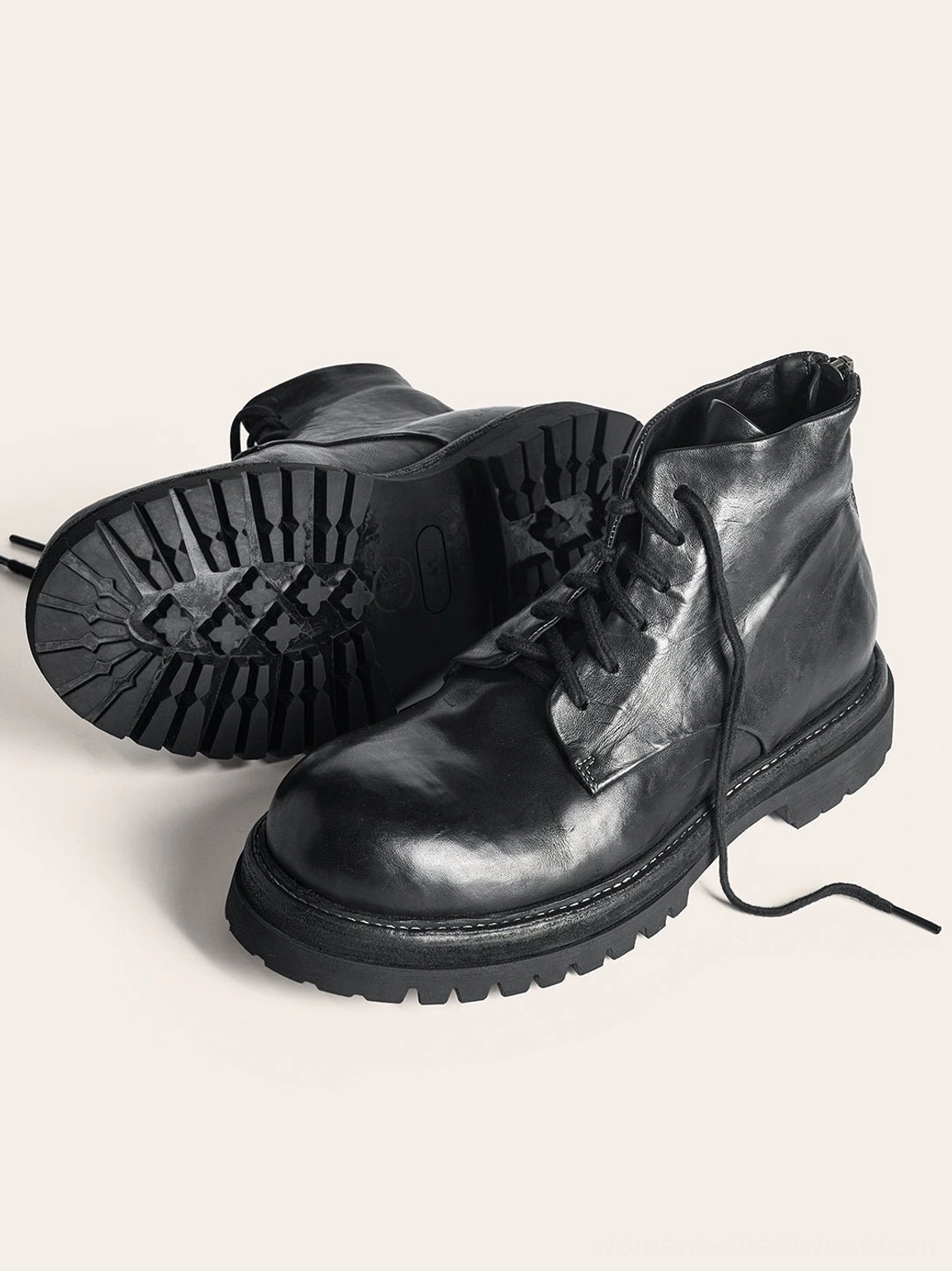 Black washed horsehide rear-zip combat boots shown from a low angle with detailed rubber sole pattern, lace-up front, and natural leather creases