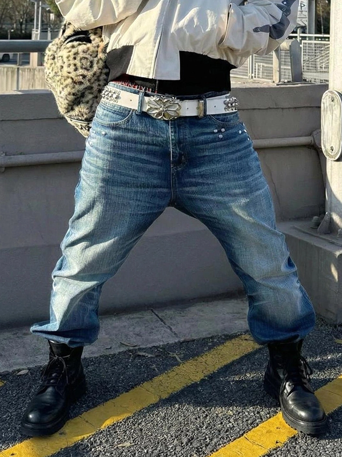 Black washed horsehide rear-zip combat boots styled with loose blue jeans, a decorative belt, and a retro streetwear outfit