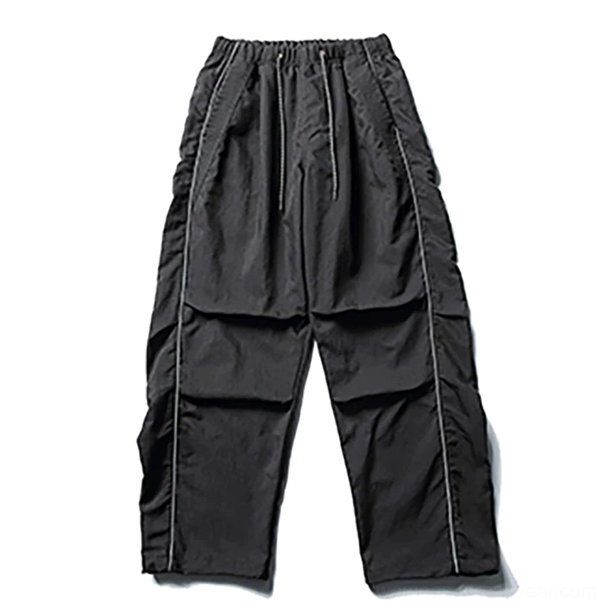 Front flat lay of black water-resistant reflective utility cargo pants with elastic drawstring waist pleated front and oversized wide-leg techwear silhouette