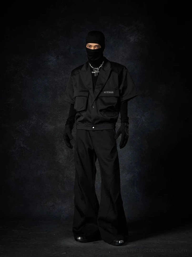 Black wave contour wide-leg streetwear trousers styled in an all-black tactical outfit with utility layers and silver chain accessory