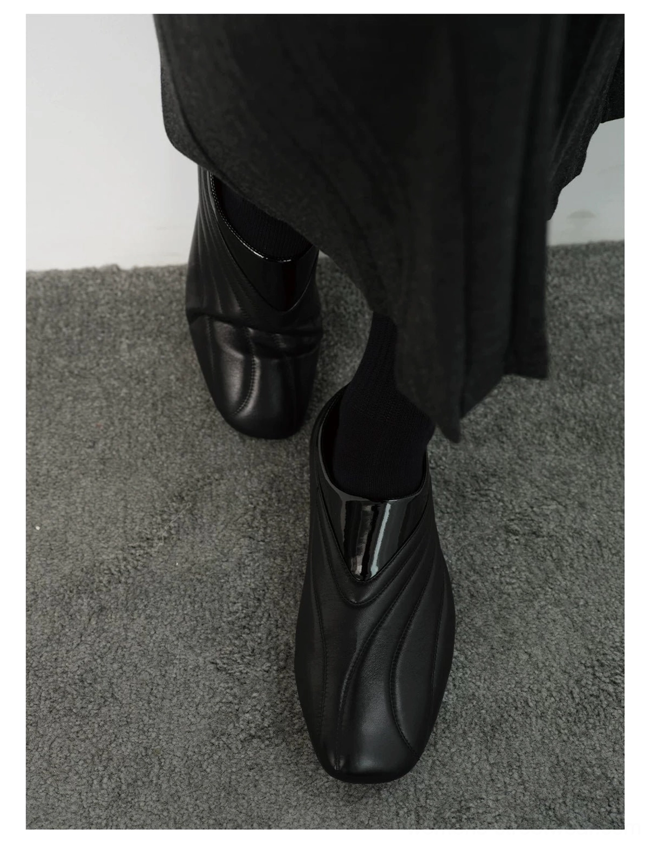 Front close-up of black wave seam leather slip-on shoes with rounded square toe and glossy collar accent