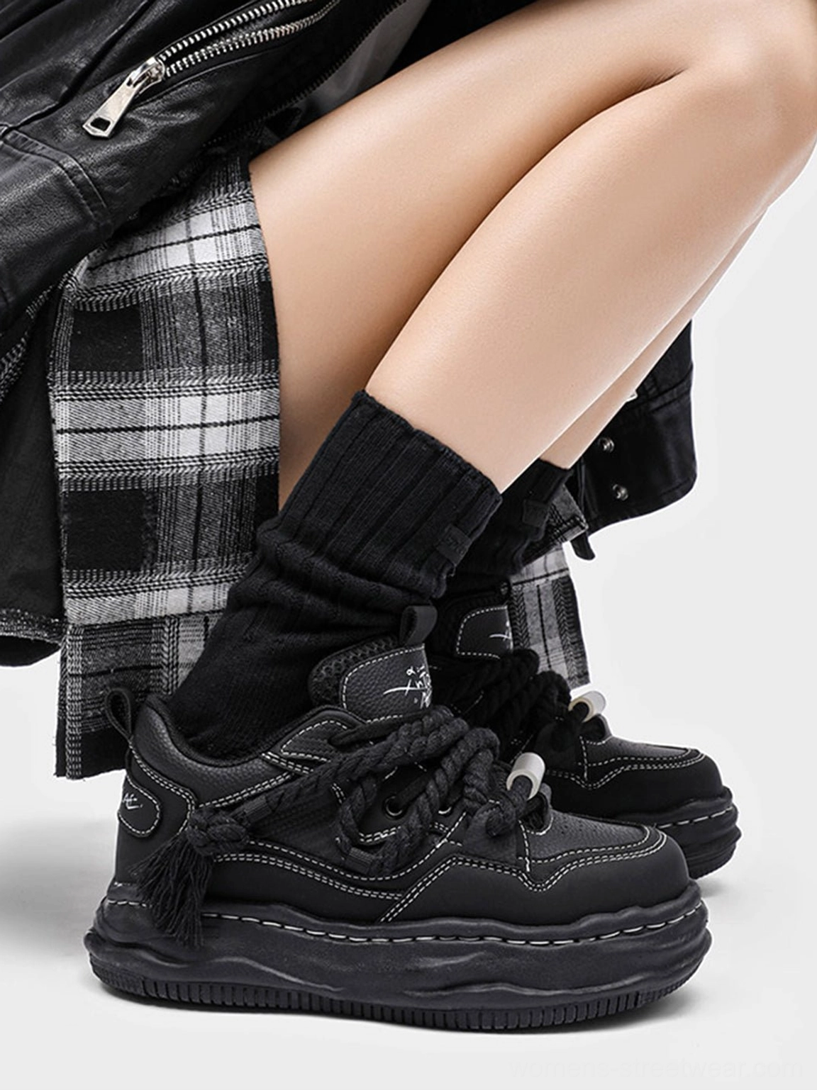 Close-up of black wavy platform sneaker with rope laces tassel heel thick outsole and stitched upper