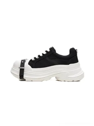 Side profile of black and white buckle platform canvas sneakers with silver toe strap, contrast toe cap, lace-up front, and chunky wave sole