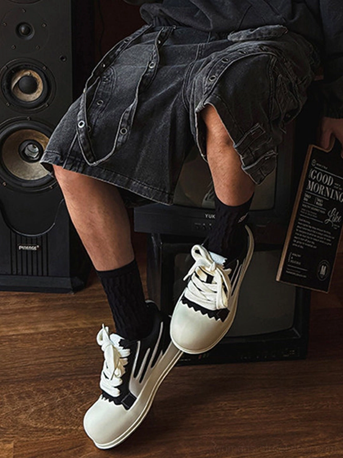 Black and white chunky platform sneakers worn with black cargo shorts and crew socks for casual streetwear styling