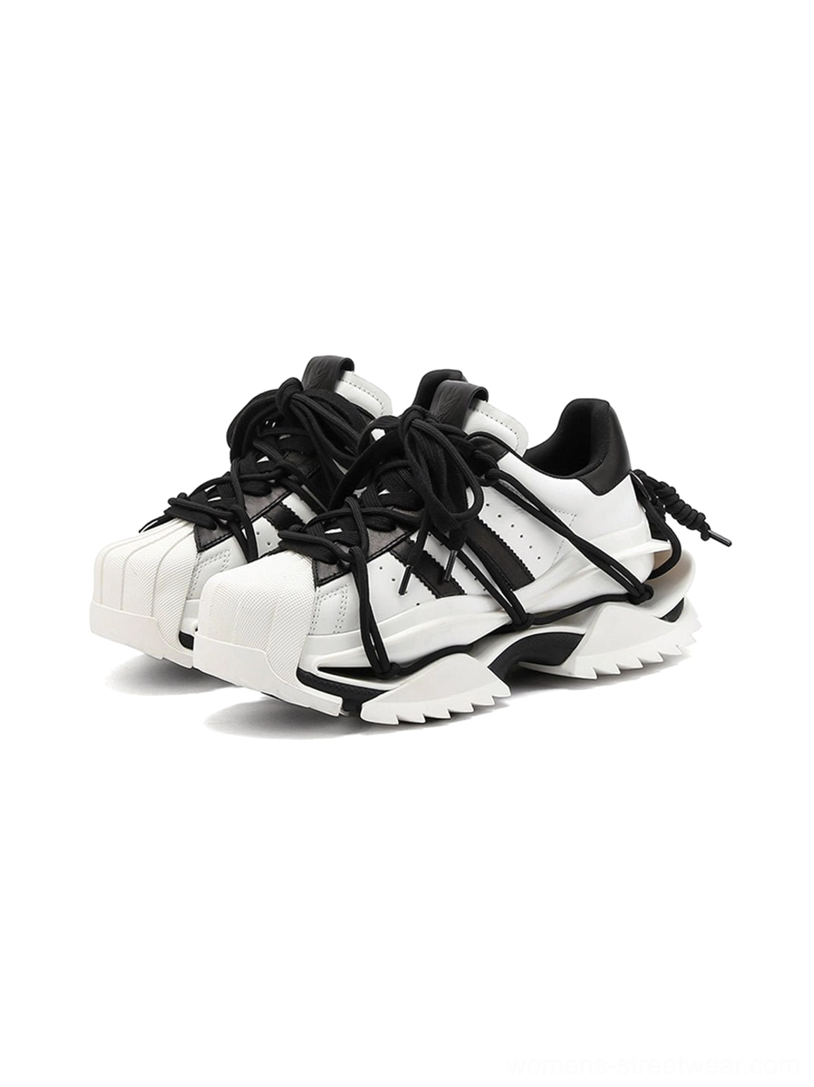 Front studio view of black and white chunky sneakers showing the rounded shell-inspired toe, layered lace-up straps, and thick sculpted white sole