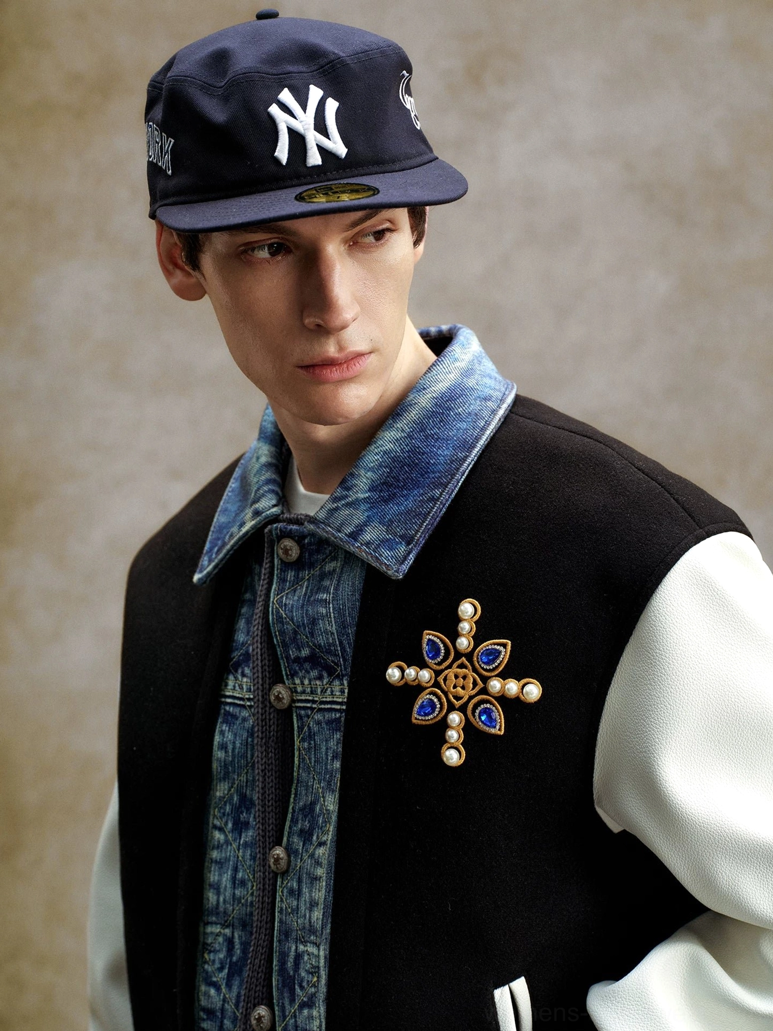Black and white denim panel embroidered varsity bomber jacket close-up with layered denim-effect collar, snap placket, and metallic chest embroidery