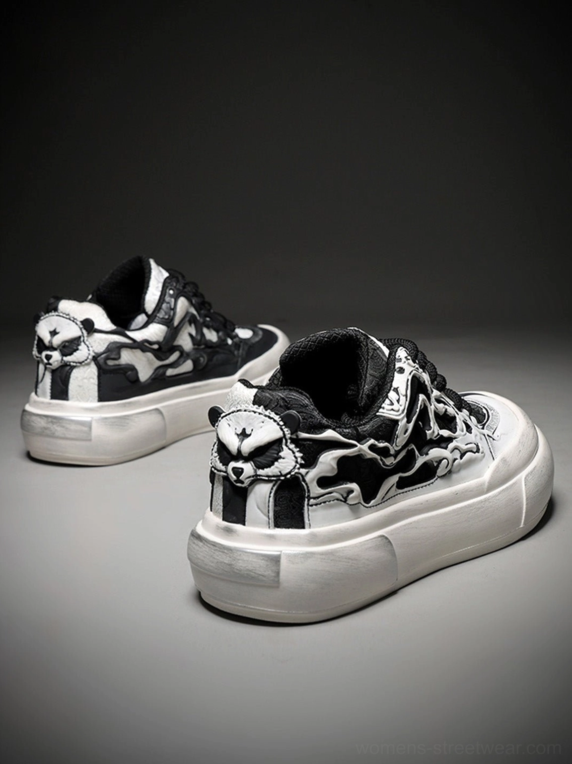 Rear three-quarter view of black and white flame platform sneakers showing matching skull heel emblem and thick platform sole