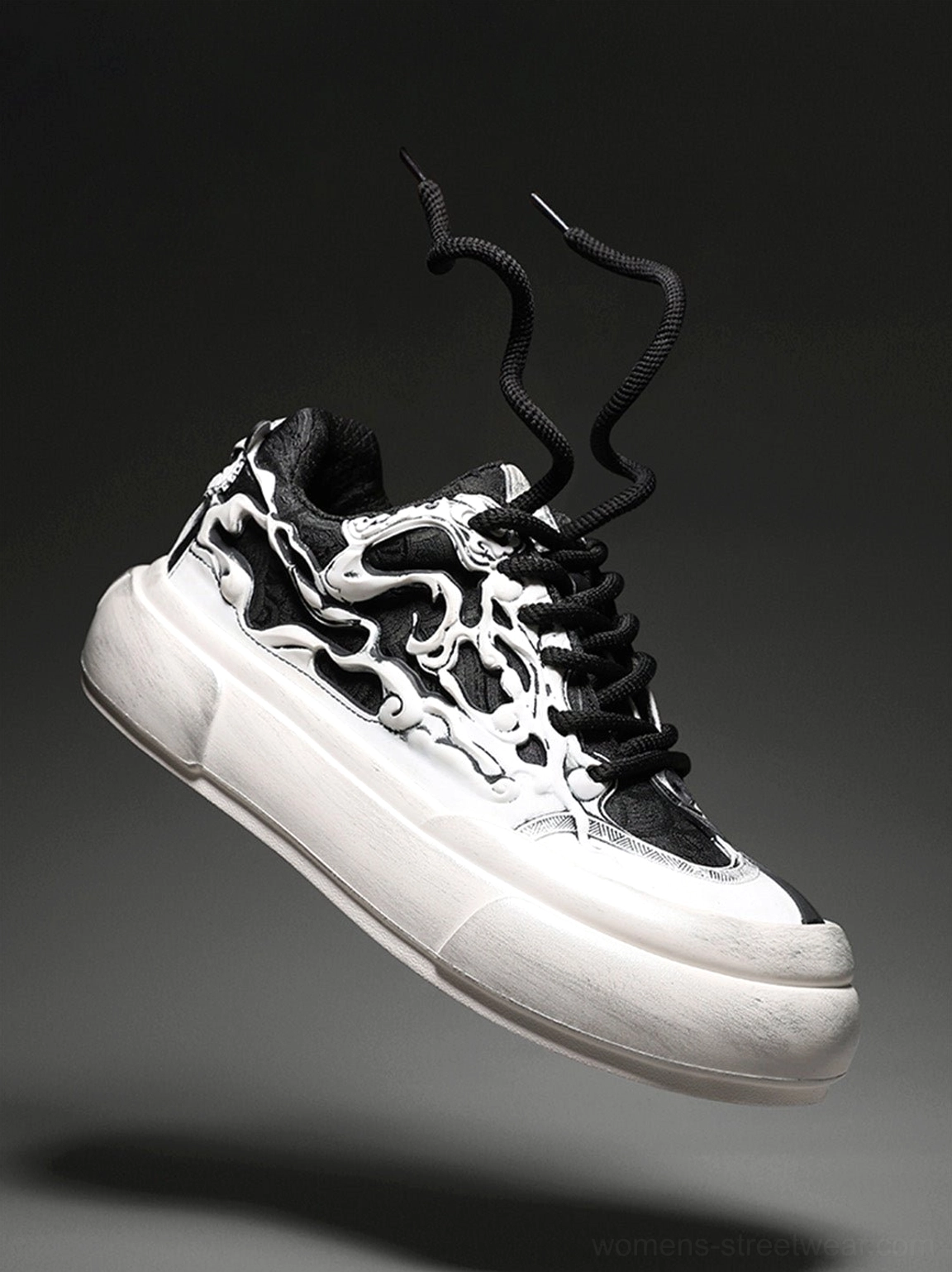 Low angle view of a black and white flame skull chunky platform sneaker with curved thick sole and loose black laces