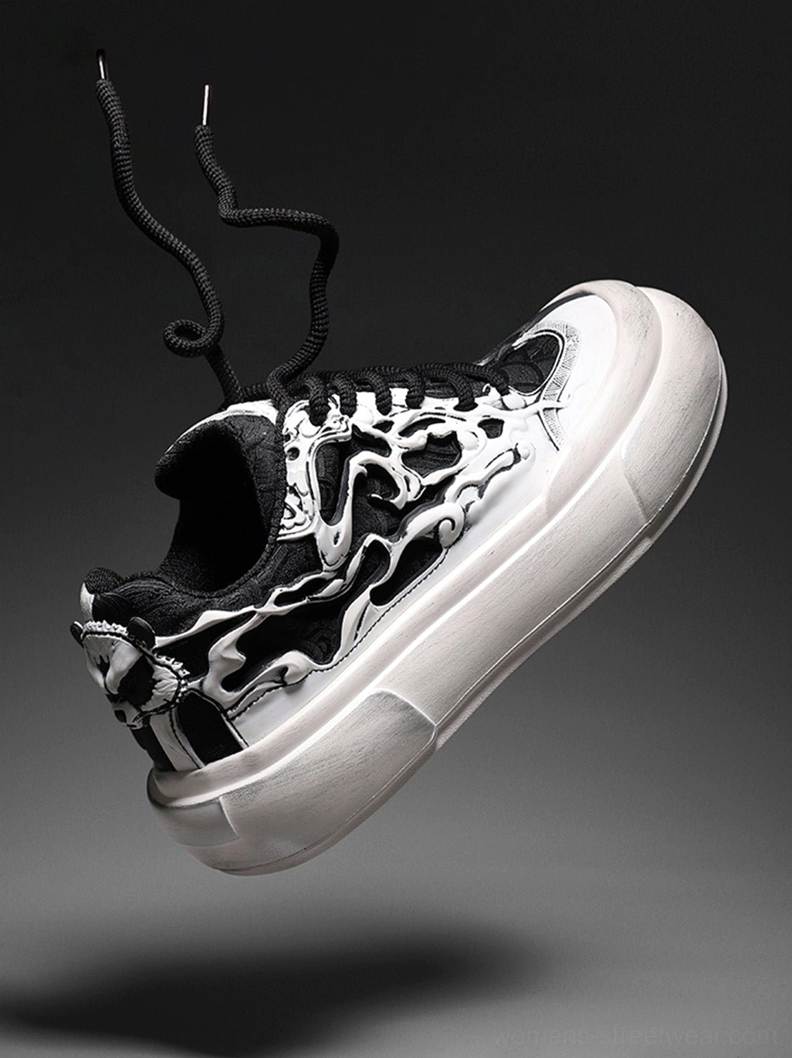 Oblique front view of a black and white flame skull platform sneaker with detailed printed upper exposed heel counter and black laces