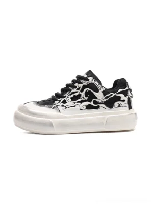 Black and white flame skull platform sneakers shown from a side three-quarter angle with chunky aged white sole and black laces