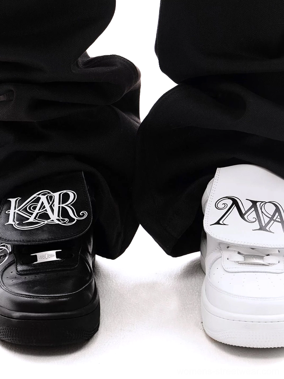 Black and white foldover tongue chunky leather sneakers worn with loose black trousers, featuring graphic tongues and matching studded midsoles
