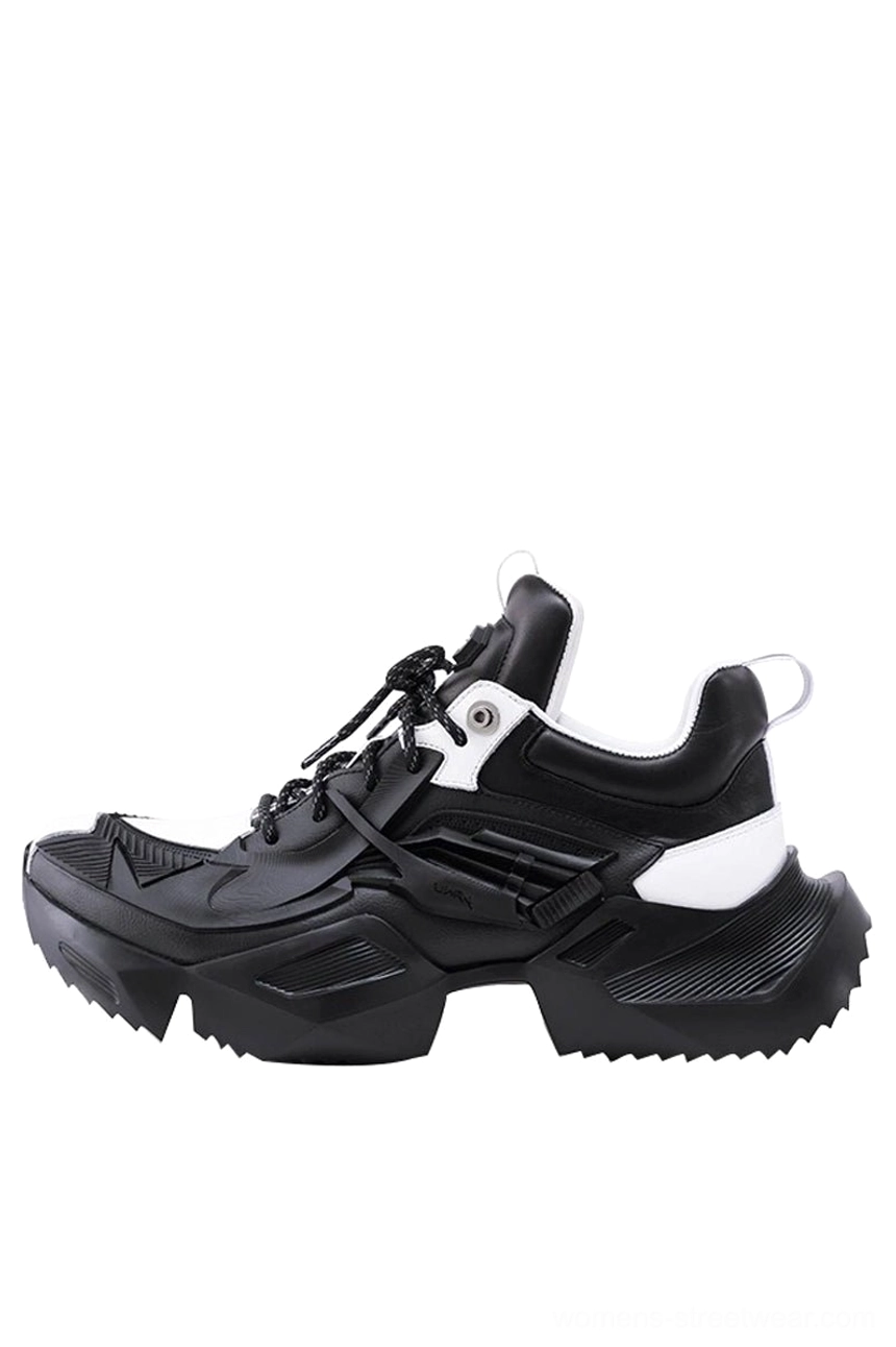 Black and white futuristic platform sneaker featuring a toggle quick-lace system, contrasting white heel panel, structured upper, and heavy-duty jagged outsole