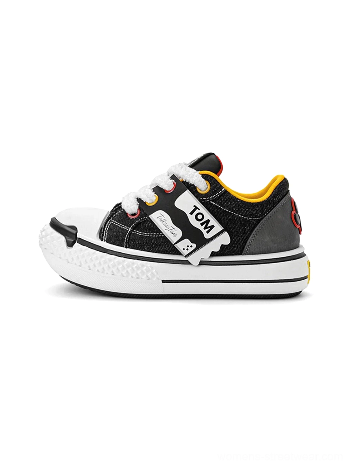 Black and white graphic chunky low-top sneakers shown in left side profile with a thick rounded PVC sole, contrast toe cap, padded collar, and yellow inner lining