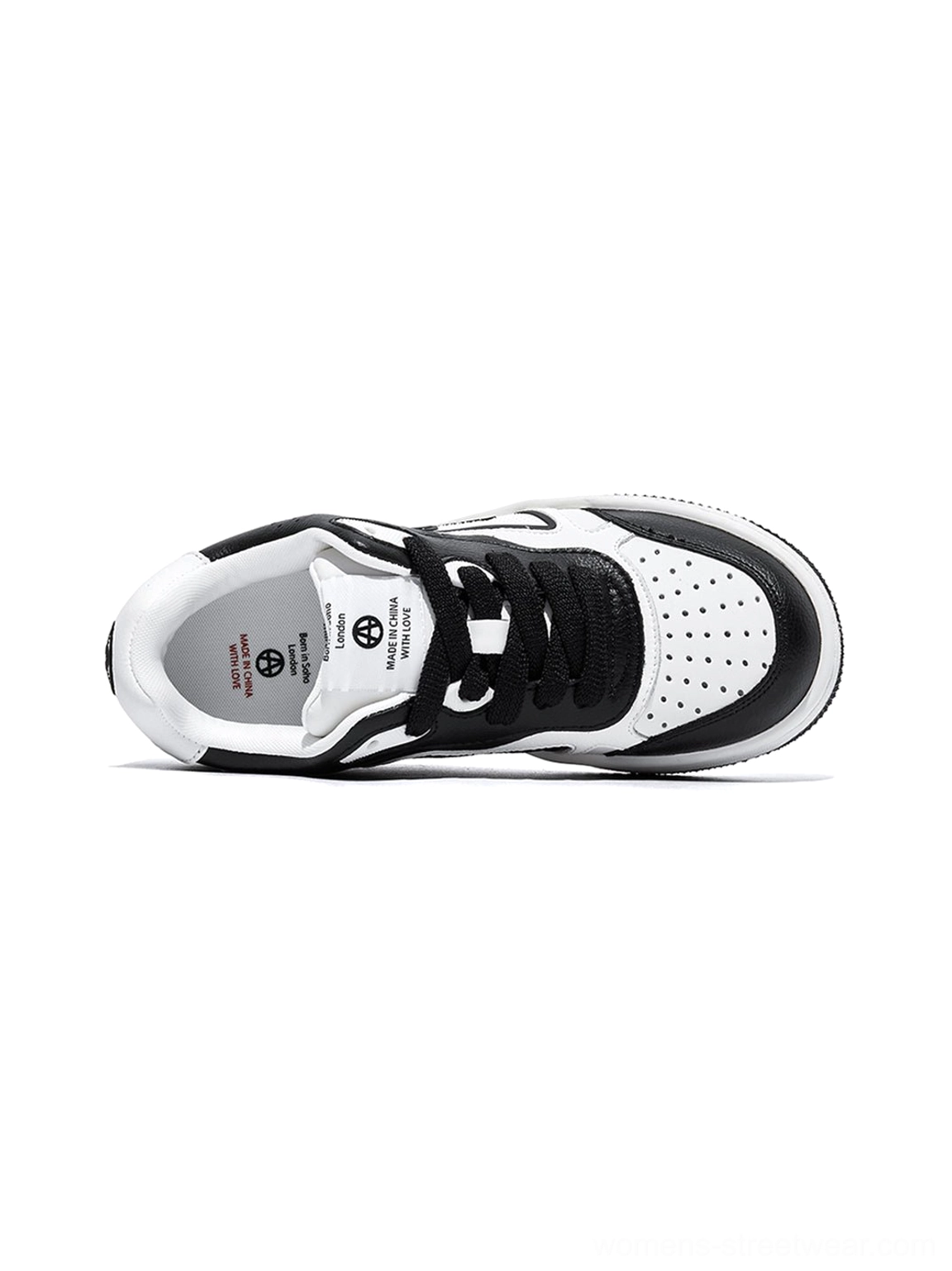 Oblique overhead view of a black and white streetwear skate sneaker showing the insole, breathable toe holes, and decorative stitching