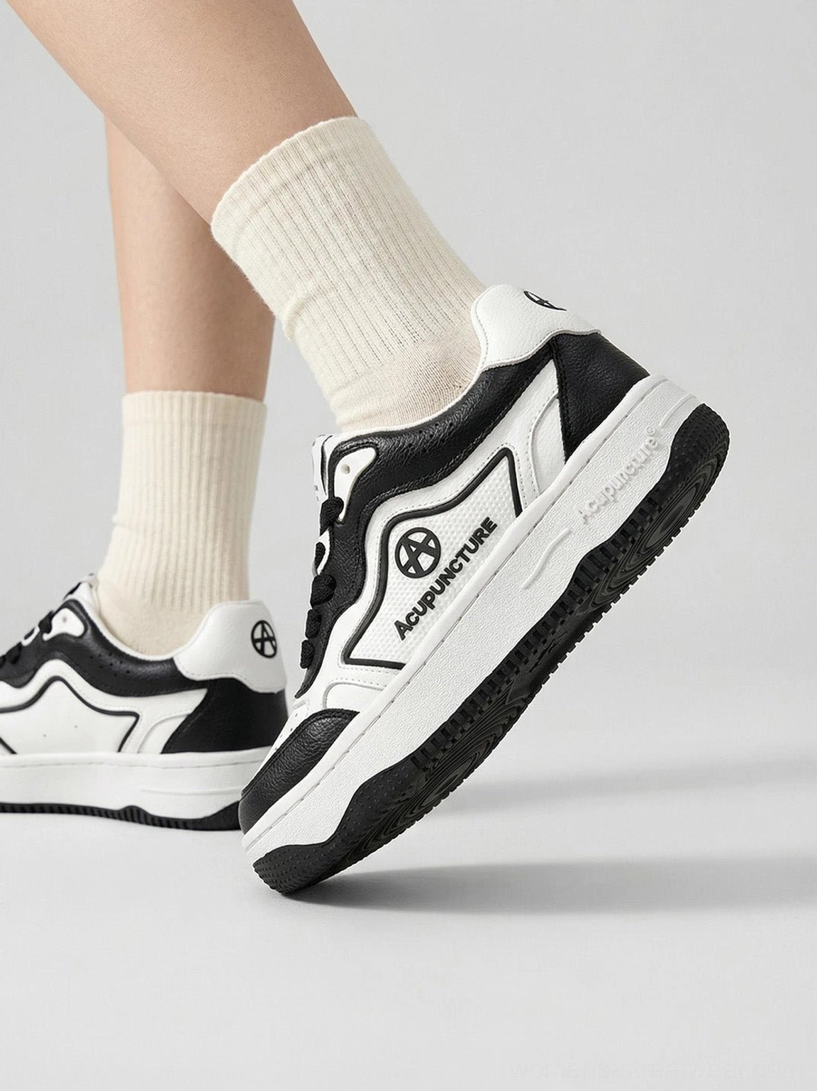 Side view of black and white logo skate sneakers worn on foot showing the thick layered rubber outsole and retro skate profile