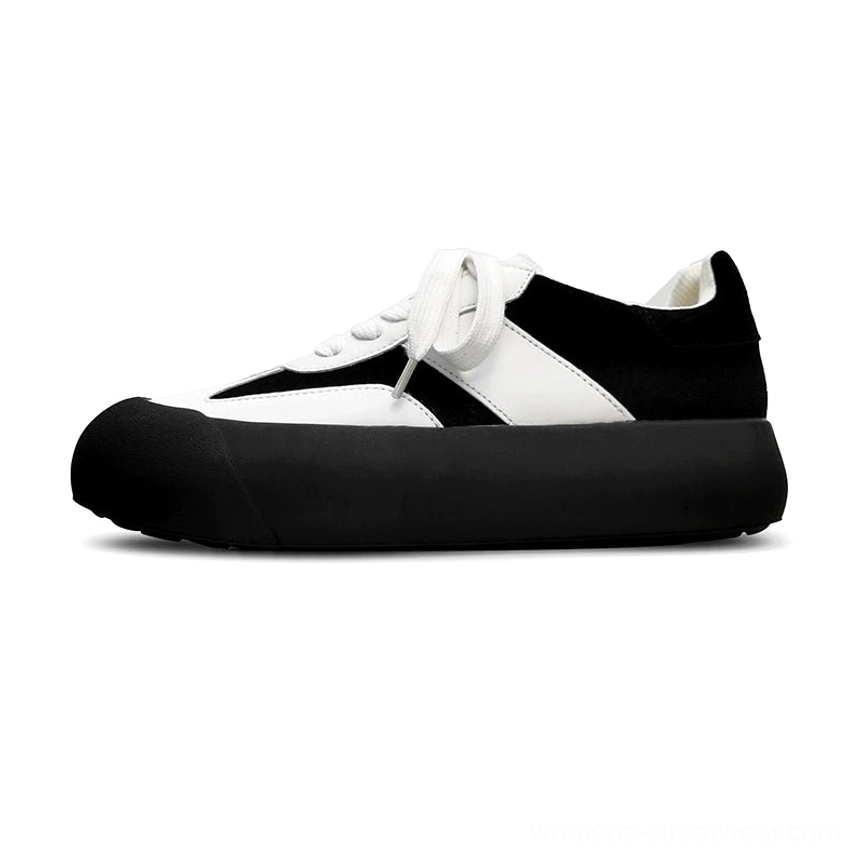 Black and white low top chunky sneakers displayed in side profile with full black platform sole and color blocked upper