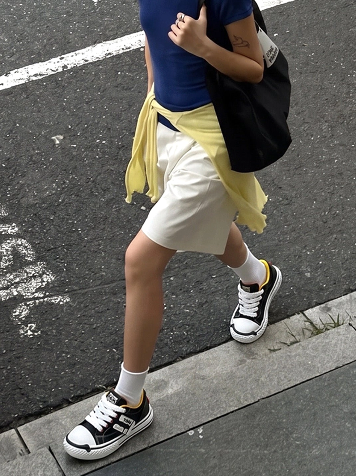 Black and white low-top chunky sneakers worn with a casual everyday outfit on an urban sidewalk