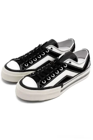 Side angled view of black and white low-top platform canvas sneakers with lace-up closure and thick off-white rubber outsole