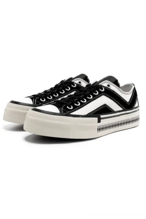 Front angled view of black and white platform canvas sneakers with chevron side detail and serrated rubber midsole trim