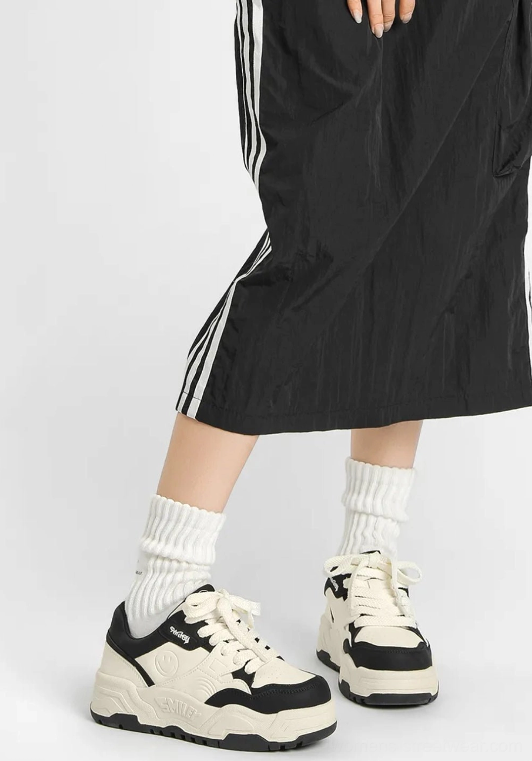 Black and white platform skate shoes styled with a striped skirt and ribbed socks featuring a star detail on the sneaker side