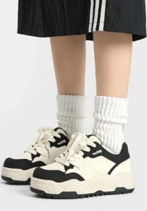 Black and white platform skate sneakers styled with white ribbed crew socks and a black sporty skirt for a Y2K streetwear outfit